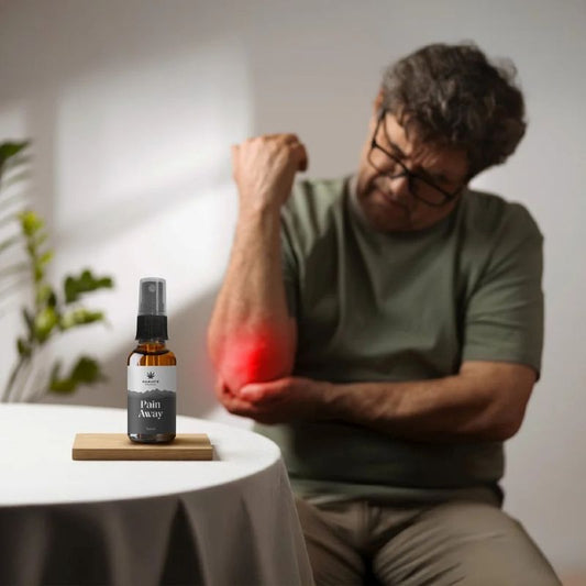 Man with a painful arm holding a bottle labeled 'Pain Away - Full spectrum CBD Oil' on a table.