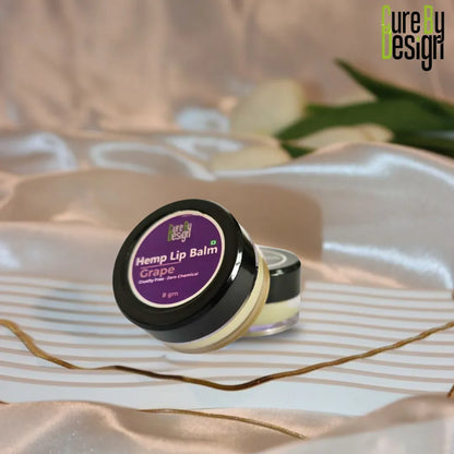 Hemp lip balm with purple label on a decorative surface, featuring 'Pure by Design' branding.
