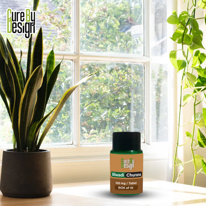 Bottle of 'Cure by Design' bilvadi churana product on a windowsill with plants