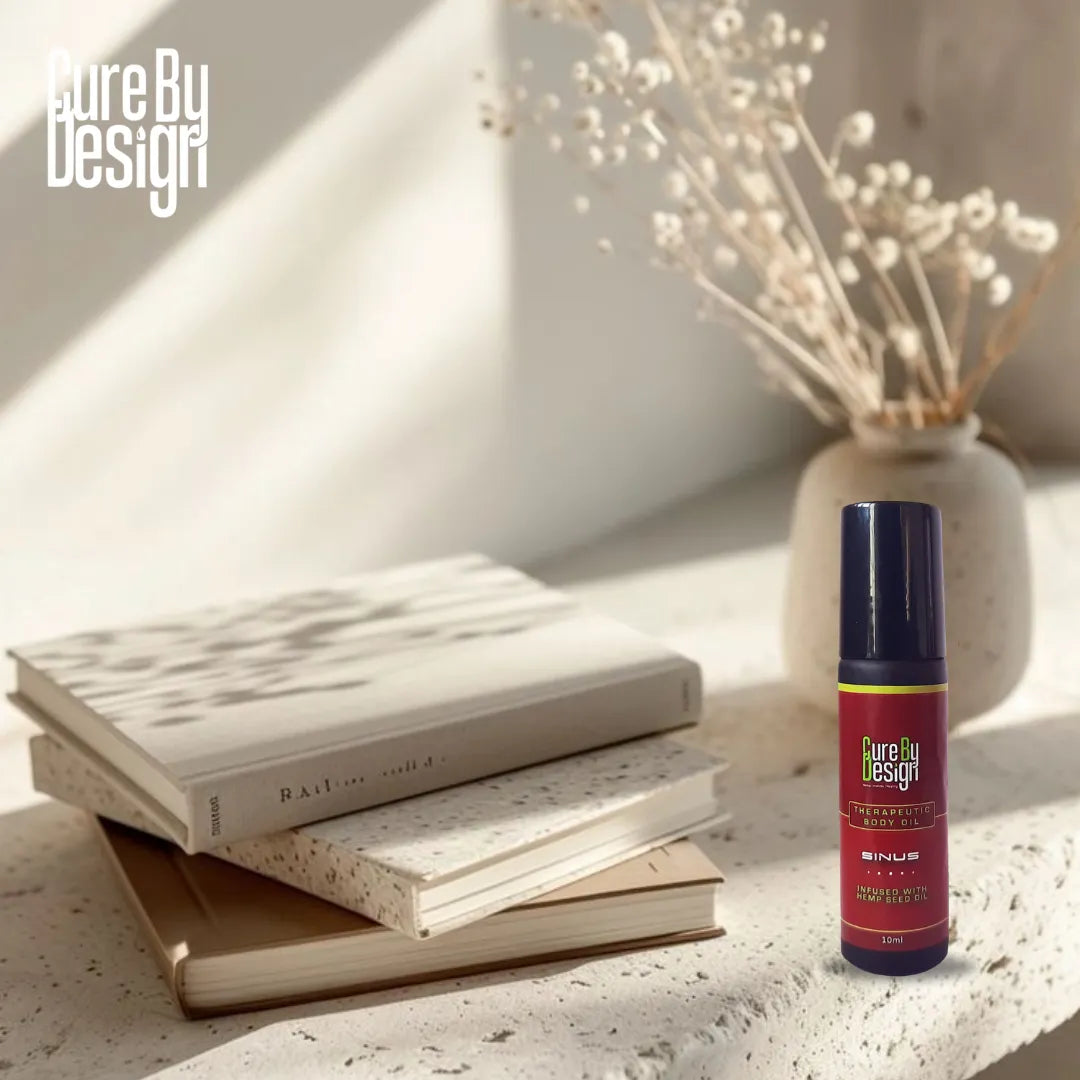 Cure By Design product next to books and a vase with dried flowers on a light surface.