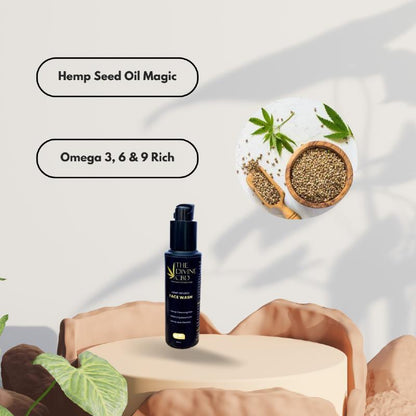 Black bottle of The Divine CBD face wash on a beige pedestal with text: "Hemp Seed Oil Magic" and "Omega 3, 6 & 9 Rich.