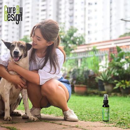 Woman holding a dog with a bottle of 'Cure by Design Hemp Spray' product on grass
