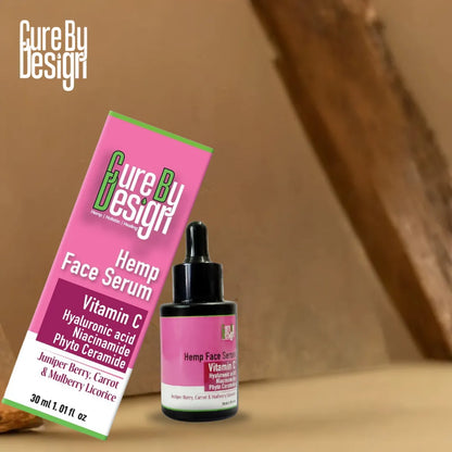 Cure By Design Hemp Face Serum with pink packaging on a wooden surface