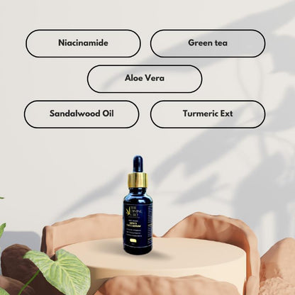 Bottle of face serum with a gold dropper cap on a beige surface, surrounded by ingredient labels.