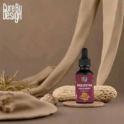 Manjistha liquid drops bottle with dropper on a brown background, featuring Cure By Design branding.