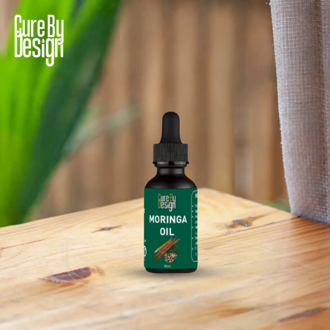 Bottle of Moringa oil from Cure By Design on a wooden surface with a blurred natural background.