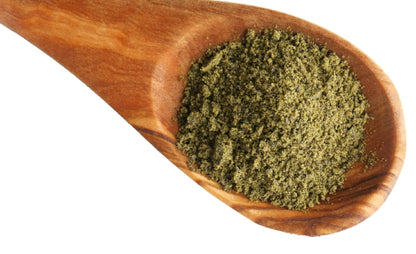 Wooden spoon filled with green powder on a white background