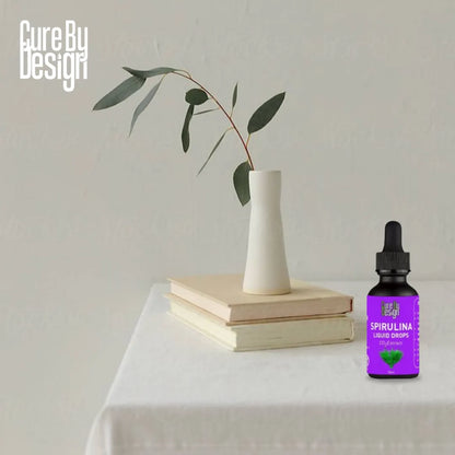 Spirulina liquid drop bottle on a table with a vase and books in the background