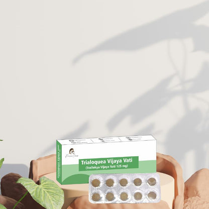 Medication box labeled "Trialoquea Vijaya Vati" with a  pack of ten tablets in front, set against a light beige background with plant shadows.