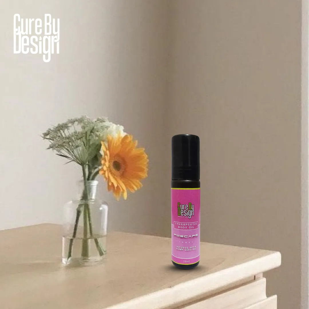 Therapeutic Body Oil PMScape by Cure by Design bottle with purple label on a surface next to a vase with flowers, against a plain wall.