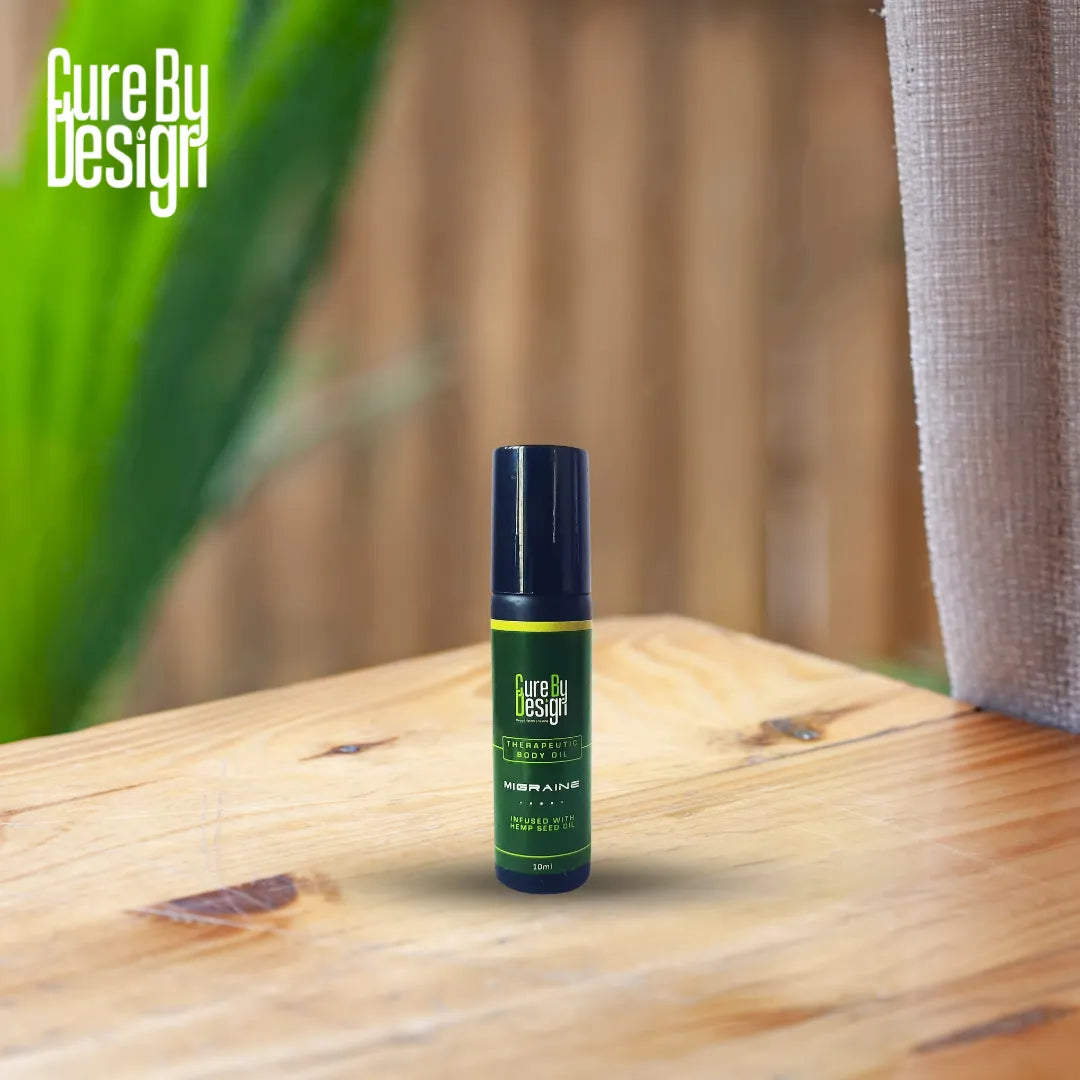 Green bottle of Therapeutic Healing Roll-on - Migraine with black cap on a wooden surface, 'Cure By Design' branding visible