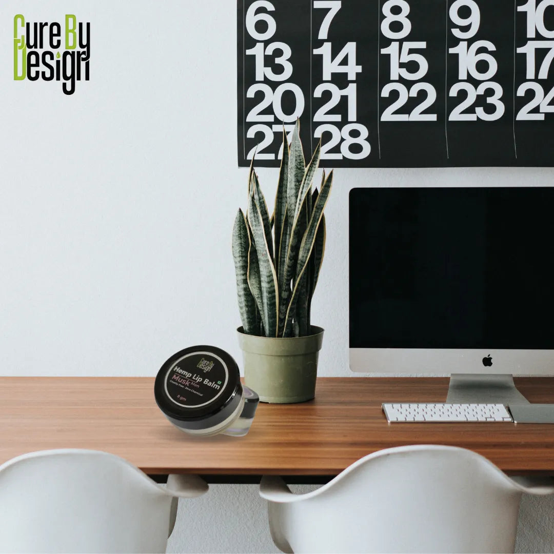 Modern office desk with a plant, container, and computer monitor, featuring 'Cure By Design' branding.